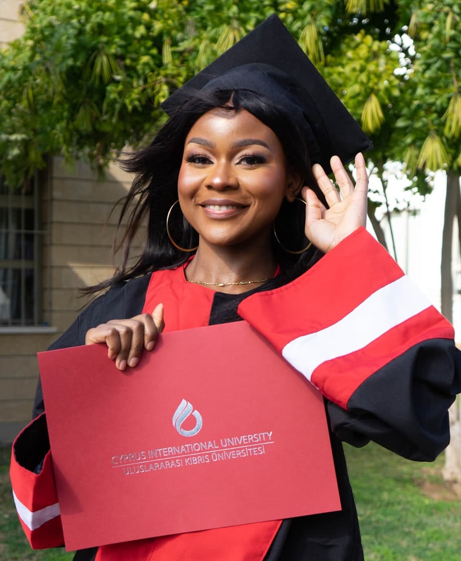 A graduate in cap and gown holding her diploma